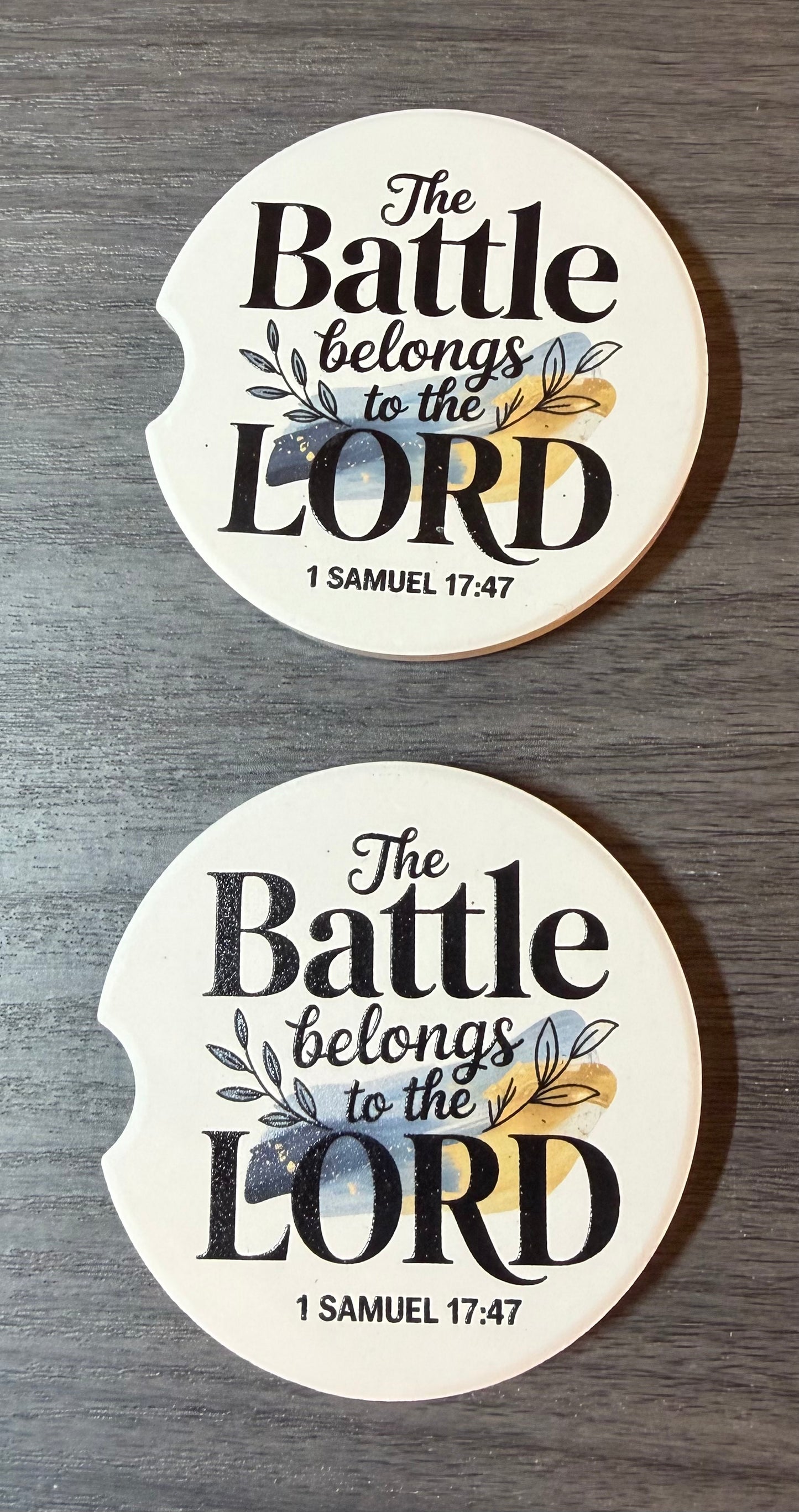 "The Battle Belongs to the Lord" Ceramic car coasters, designed to fit most cup holders, are absorbent and help keep cars clean. They feature a vibrant design and are a great gift for car lovers.